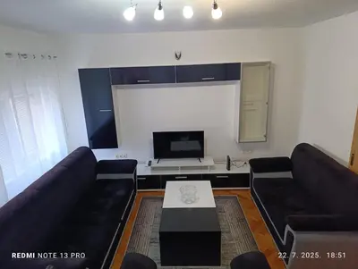 a living room with black couches and a tv at Apartman Omar in Bihać