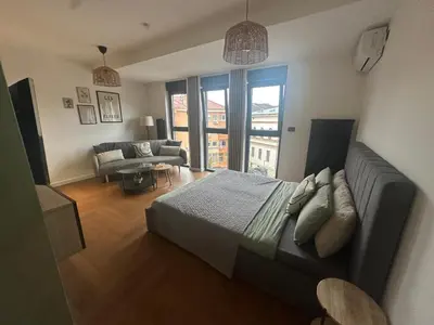 a bedroom with a bed and a living room with a couch at Zs Apartment in Tuzla