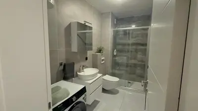 a white bathroom with a toilet and a sink at Zs Apartment in Tuzla