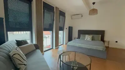 a bedroom with a bed and a couch and a glass table at Zs Apartment in Tuzla