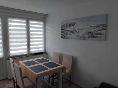 a dining room with a table and chairs and a painting at Apartman Breskvica in Bihać