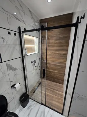 a shower with a wooden door in a bathroom at Suite M in Livno