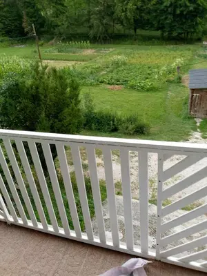 a white fence on a porch with a view of a yard at Secret garden in Visoko