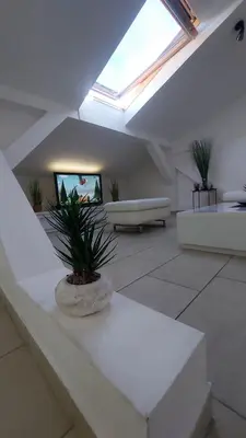 a living room with a skylight and a couch and plants at Mansarda Apartman Diva in Prijedor