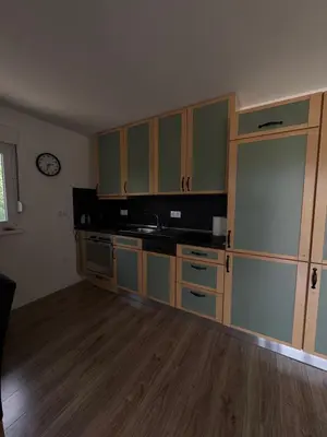 a kitchen with green cabinets and a clock on the wall at Sašina kuća in Livno