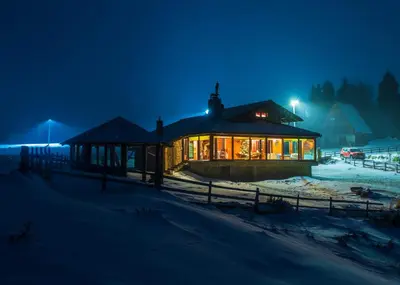 a house in the snow at night at Planinska kuća 