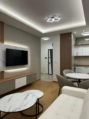 a living room with two tables and a flat screen tv at GRAĐUS Deluxe Apartmani in Kotor-Varoš