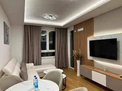 a living room with a white couch and a flat screen tv at GRAĐUS Deluxe Apartmani in Kotor-Varoš
