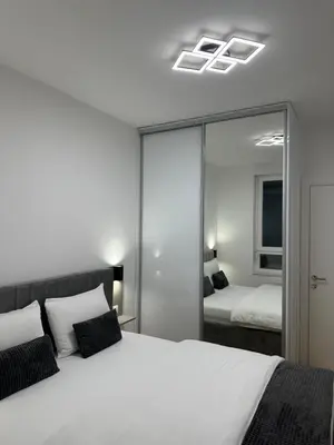 a bedroom with a large white bed and a mirror at GRAĐUS Deluxe Apartmani in Kotor-Varoš