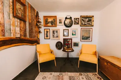 two chairs and a clock on a wall with pictures at Kuća s osmijehom in Livno