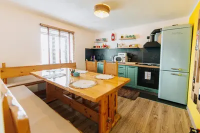 a kitchen with a wooden table and green cabinets at Kuća s osmijehom in Livno