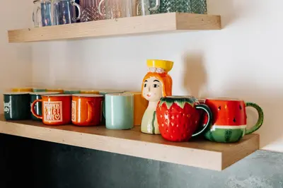 a shelf with different colored mugs on it at Kuća s osmijehom in Livno