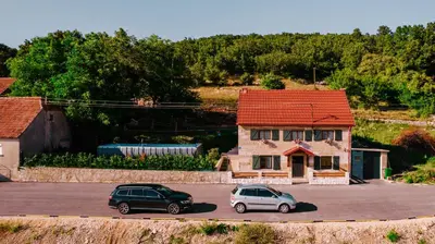 two cars parked in a parking lot in front of a house at Kuća s osmijehom in Livno