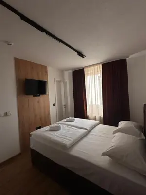 a bedroom with a large white bed with a window at Hotel Fortuna in Gradačac