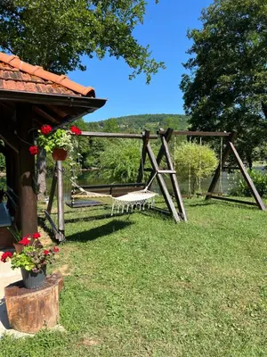 a wooden swing in the grass next to a house at Villa Emilija Krupa na Vrbasu