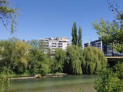 a bridge over a river with buildings in the background at Sunny River BL in Banja Luka