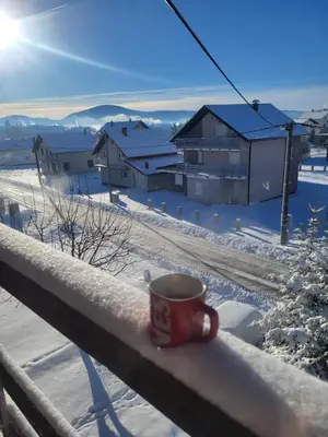 a cup of coffee sitting on a rail in the snow at N&M Mountain Escape in Kupres