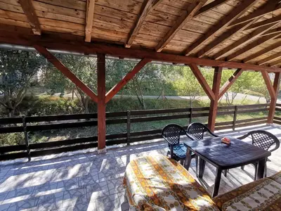 a patio with a table and chairs and a wooden roof at Kuća na dan in Bosansko Grahovo