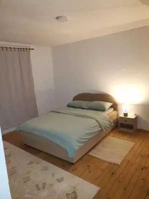 a bedroom with a bed and a lamp on a wooden floor at Kuća na dan in Bosansko Grahovo