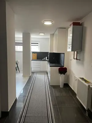 a kitchen with white cabinets and a black floor at Apartman Sara in Teslić