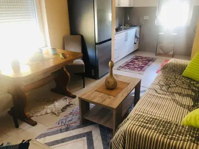 a living room with a table and a kitchen at Apartment Medi in Visoko