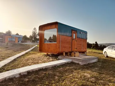 a tiny house sitting in a field next to a car at Petrovf Place