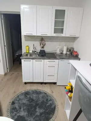 a kitchen with white cabinets and a sink and a rug at Apartman ARDA in Jajce