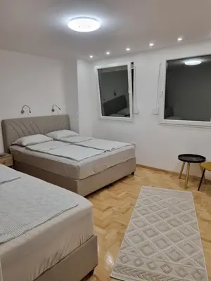 two beds in a room with two windows at Palada apartment in Banja Luka