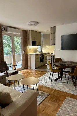 a living room with a couch and tables and a kitchen at Palada apartment in Banja Luka