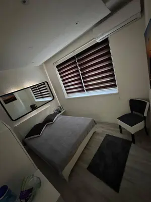 a bedroom with a bed and a chair and a window at Luxury Apartman Dzafic in Sanski most