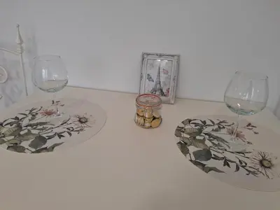 a table with two wine glasses and a picture at Apartman TEA in Ivišovo Greblje