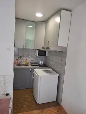 a small kitchen with white cabinets and a refrigerator at Apartman TEA in Ivišovo Greblje
