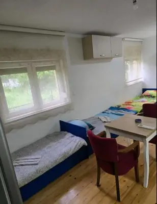 a room with two beds and a table and a table and chairs at Le Solei Apartment in Visoko