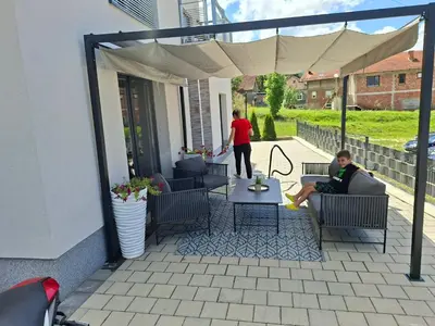 two people sitting on a patio under an umbrella at Villa Laura in Gornji Vakuf