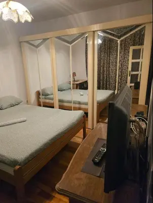 a room with two beds and a desk with a television at Pyramid Apartment in Visoko