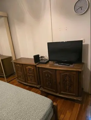 a television on a wooden cabinet in a bedroom at Pyramid Apartment in Visoko