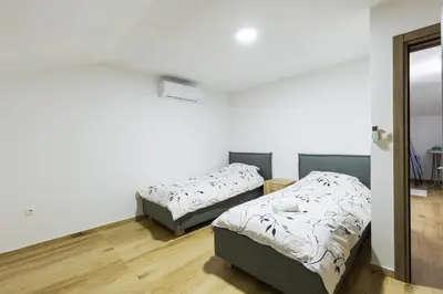 two beds in a room with white walls and wooden floors at Villa Zeleno Brdo in Visoko