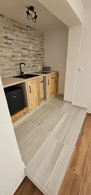 an empty kitchen with wooden cabinets and a sink at Studio Šumska prica in Livno