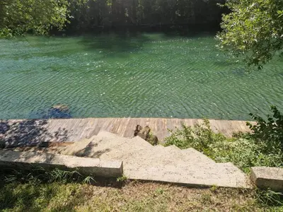 a body of water with a wooden dock in front of it at Fikro's Resort in Kulen Vakuf