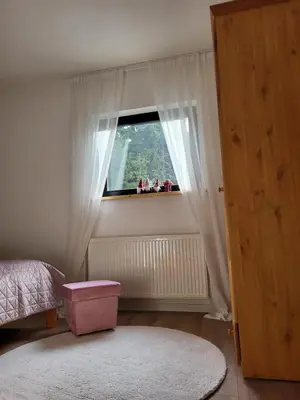 a bedroom with a window with white curtains and a pink stool at Friends 2 Vlašić in Vlasic