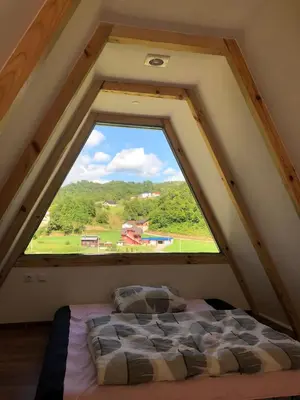 a bed in a attic with a large window at Vikednica ZEA