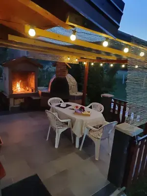 a table and chairs on a patio with a fireplace at Country House Bijela Voda in Bihać
