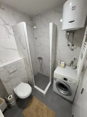 a bathroom with a shower and a washing machine at Apartman Premium in Doboj
