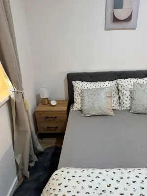 a bedroom with a bed with pillows and a table at Apartman Sofija in Doboj