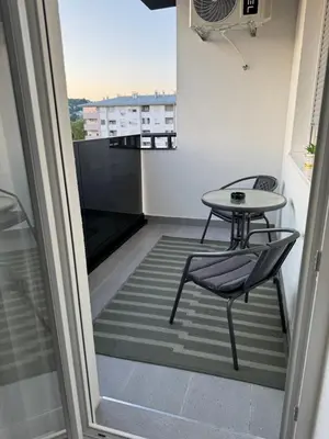 a small balcony with a table and a chair at Apartman Sofija in Doboj