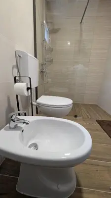 a white bathroom with a toilet and a sink at River`s Song Cottage Jajce in Jajce