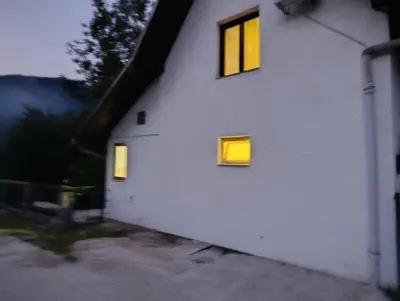a white building with two windows on the side of it at River`s Song Cottage Jajce in Jajce