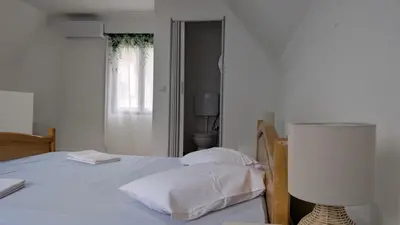 a bedroom with a bed with white sheets and a lamp at River`s Song Cottage Jajce in Jajce