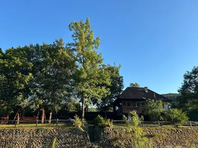 a house in a field with trees and a fence at Krivaja River Retreat - Jacuzzi, Pool and Basketball