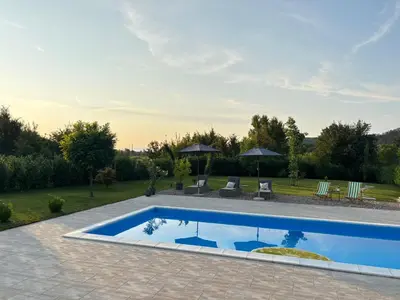 a pool in a yard with chairs and umbrellas at Villa Stone House